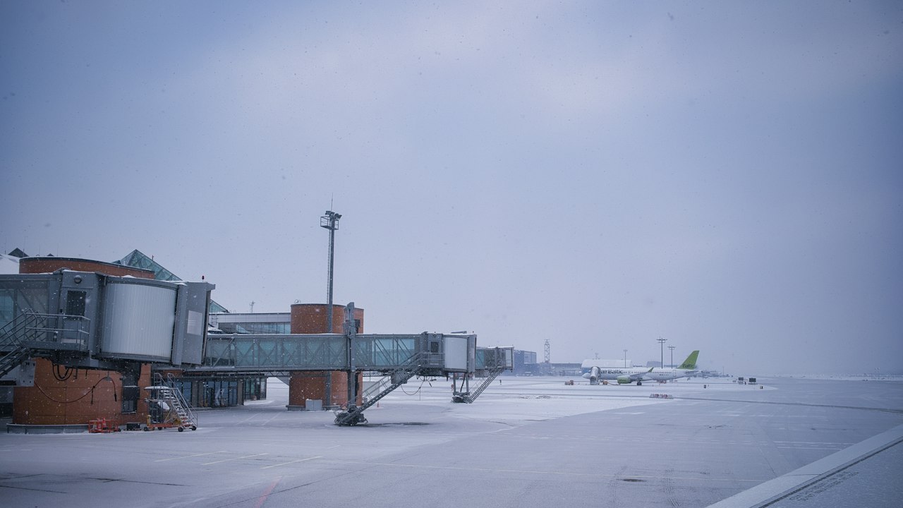 Jet bridges and an aircraft at a snow-covered terminal apron in the blue light of dusk
